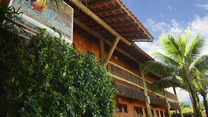 A traditional building with a thatched roof and wooden balconies, surrounded by lush greenery.