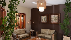 A cozy living room with two sofas, a wooden coffee table, and a hanging light fixture. - Pousada Moryba (São Sebastião)