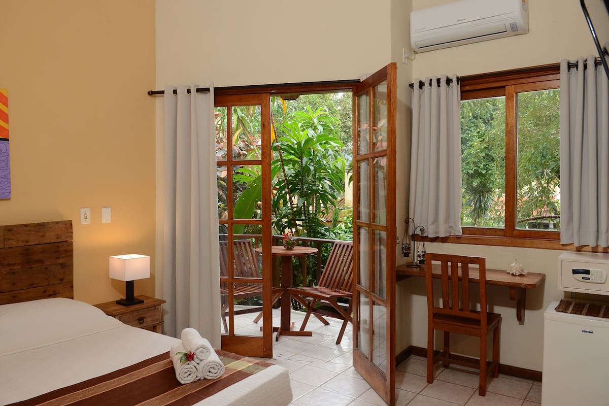 Una habitación de hotel con cama, escritorio, silla, mesa y ventana con cortinas.