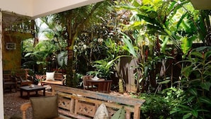 An indoor garden with wooden furniture and lush tropical plants. - Pousada Moryba (São Sebastião)