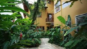 A narrow stone pathway leading to a building with balconies, surrounded by lush greenery. - Pousada Moryba (São Sebastião)