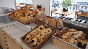 Un bufé con diversas opciones de panadería, incluyendo pasteles, pan y postres.