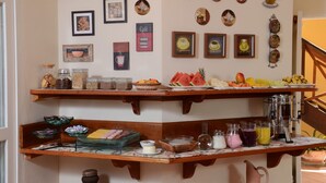 Zona de petit esmorzar amb diversos aliments i begudes, quadres a la paret i una màquina de cafè.