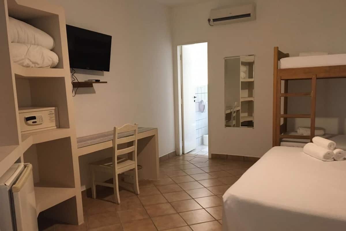 Una habitación de hotel con una cama, un escritorio, un televisor y un armario.