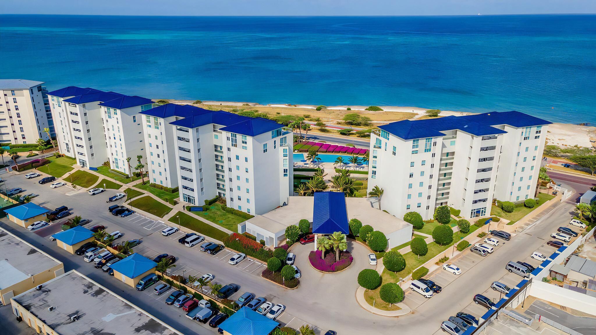 Un hôtel de grande hauteur, avec de nombreux étages, un parking et une vue sur la plage.