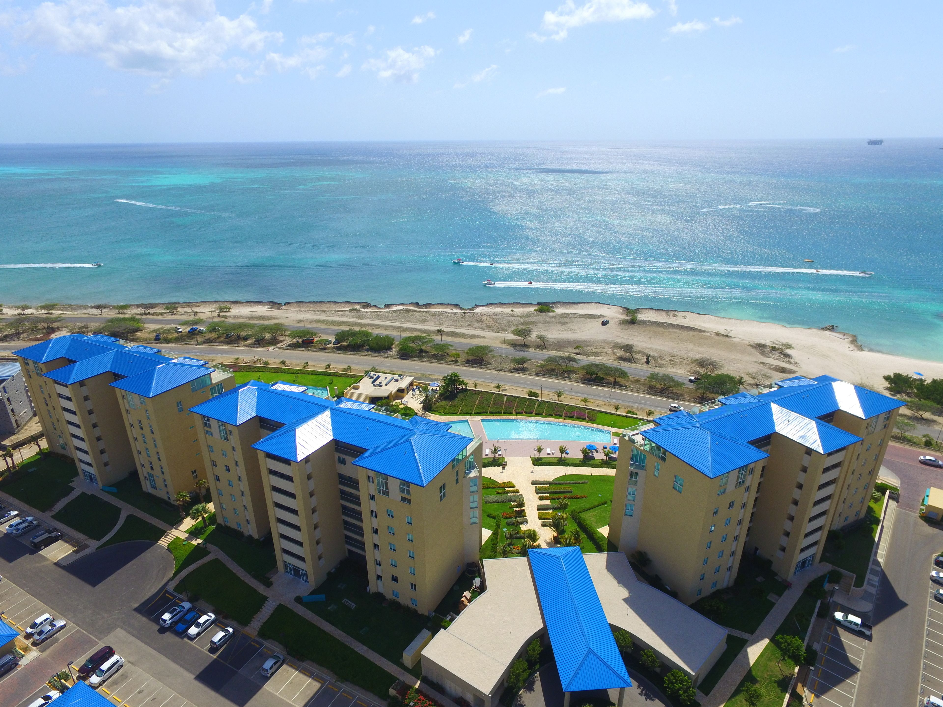 Un hôtel de grande hauteur, avec des toits bleus, qui offre une vue sur une plage et l’océan.