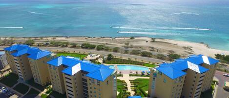 A high-rise hotel with blue roofs overlooking a beach and ocean.
