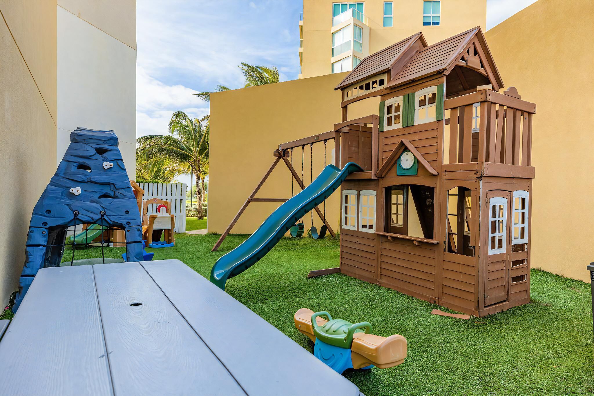 A children's play area with a slide, climbing structure, and a wooden playhouse.