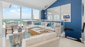 A modern living room with a large window, a sofa set, a coffee table, and a blue accent wall.
