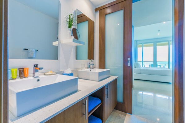 A modern bathroom with two sinks, a mirror, and a potted plant.