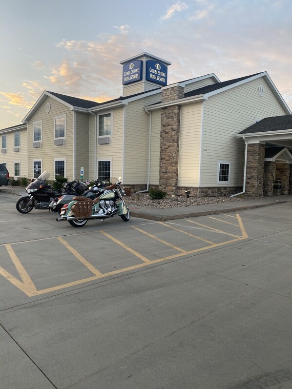 Hotel & Suites Cobblestone con aparcamiento y motocicletas estacionadas al frente.