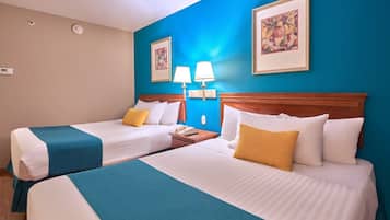 A hotel room with two beds, each with a blue and white bedspread, a wooden headboard, and a nightstand with a lamp and a phone.