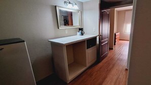 A narrow kitchen with a white countertop, a mirror above it, and a wooden door leading to another room. - Hotel Sierra by HP Hotels (San Luis Potosi)