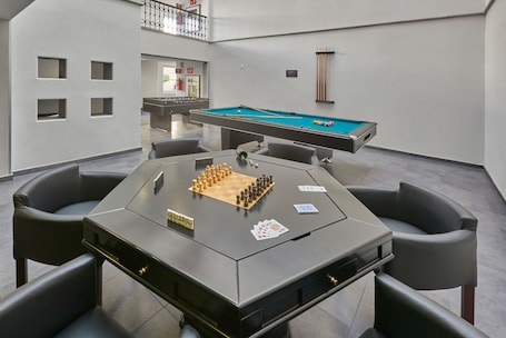 A pool table with billiards balls, a pool cue, and a chessboard with pieces.
