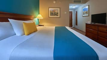 Habitación de hotel con una cama grande, un aparador de madera, un televisor y un cuadro en la pared.