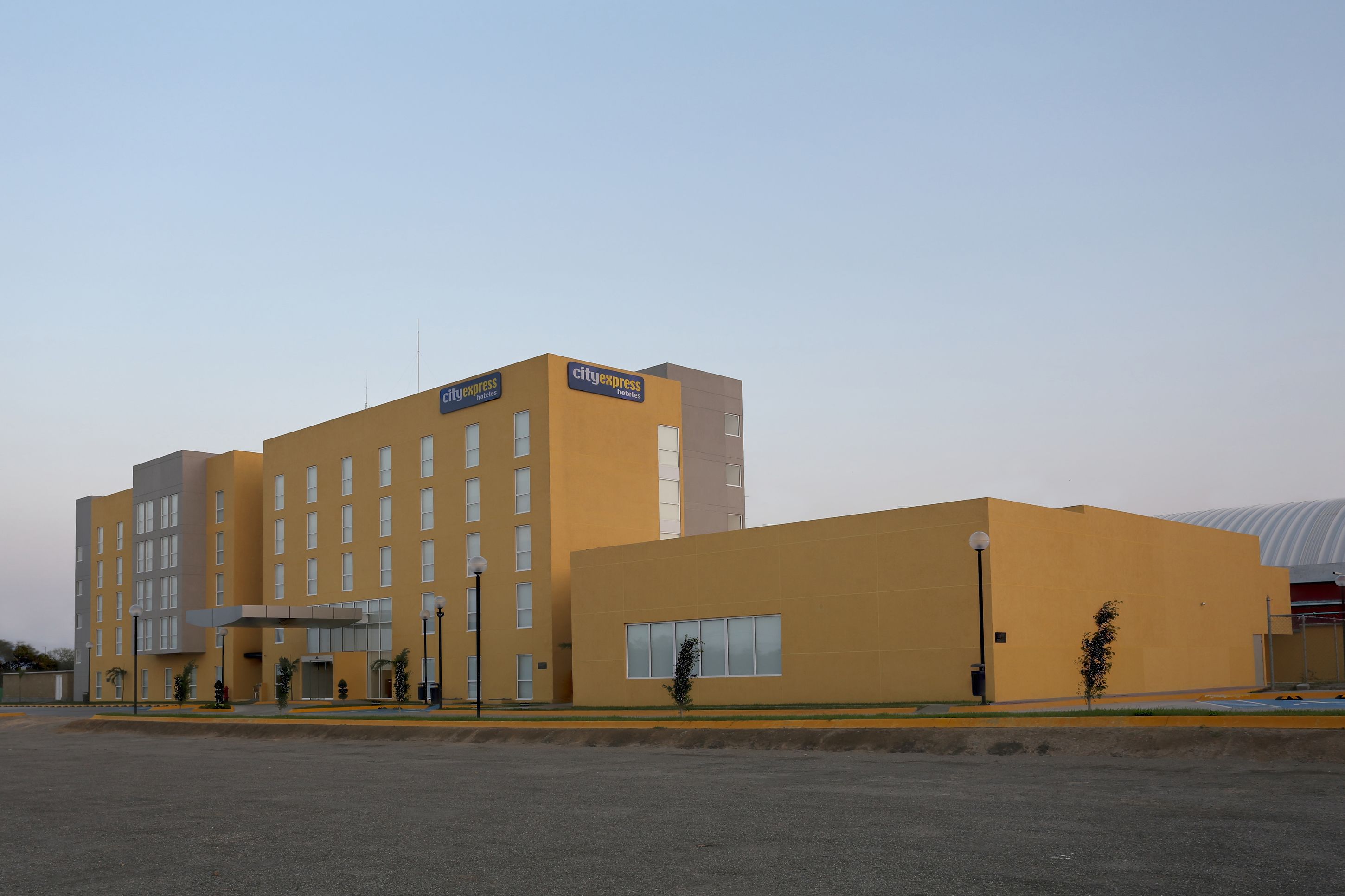 A modern hotel with a yellow facade, multiple floors, and a covered entrance area.