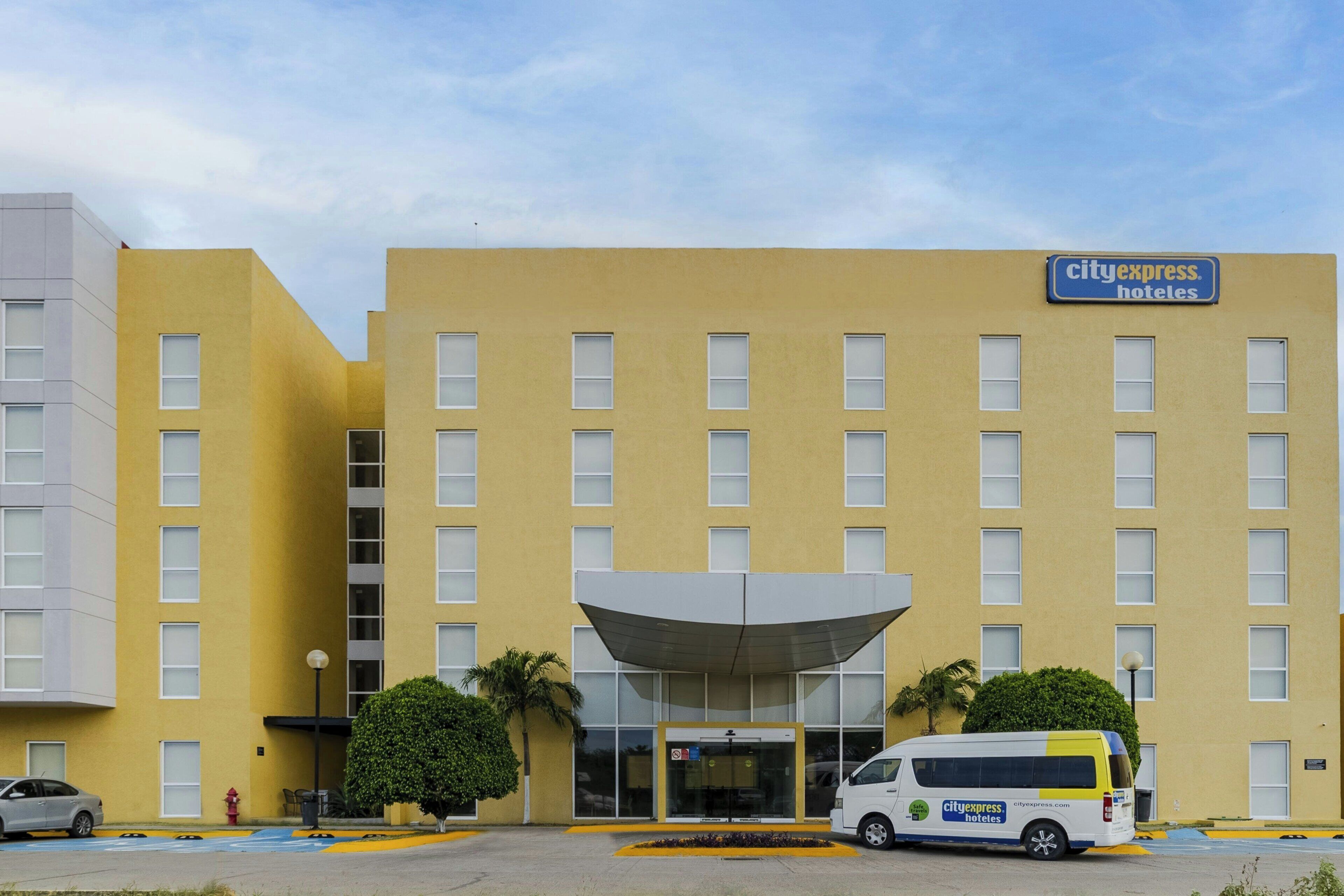 A CityExpress Hotel building with a yellow facade, multiple windows, and a covered entrance.