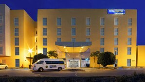 Een CityExpress Hotel met een moderne gevel, een overdekte ingang en een parkeerplaats met een bestelwagen.