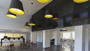 Een ruime lobby met moderne, zwart-gele hanglampen, een receptiebalie en meerdere zithoeken.