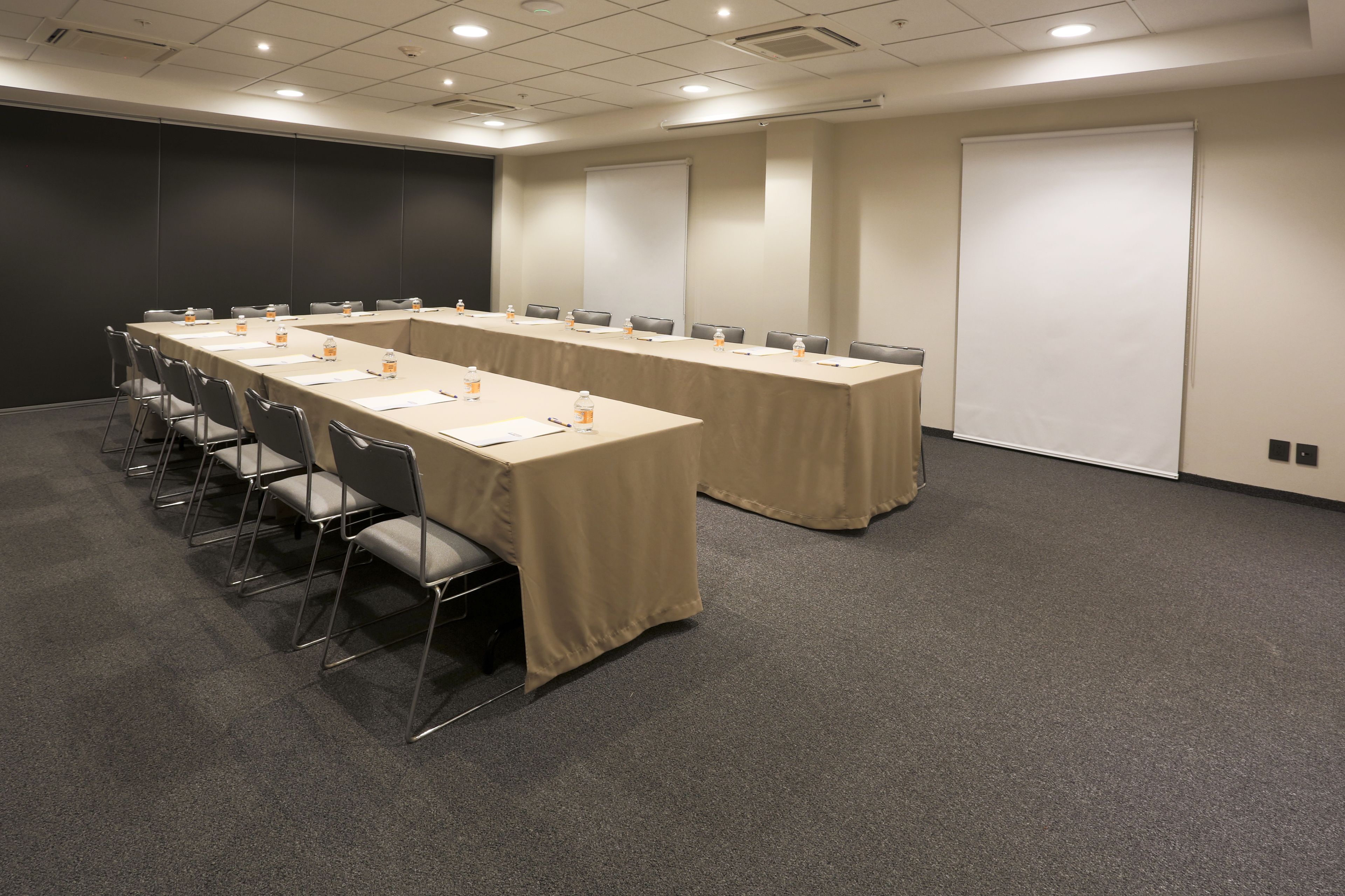 Una sala de conferències amb una taula llarga, cadires i una pantalla projectora.