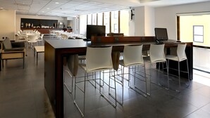 Et moderne spiseområde med en lang disk, barstole og et køkken i baggrunden.