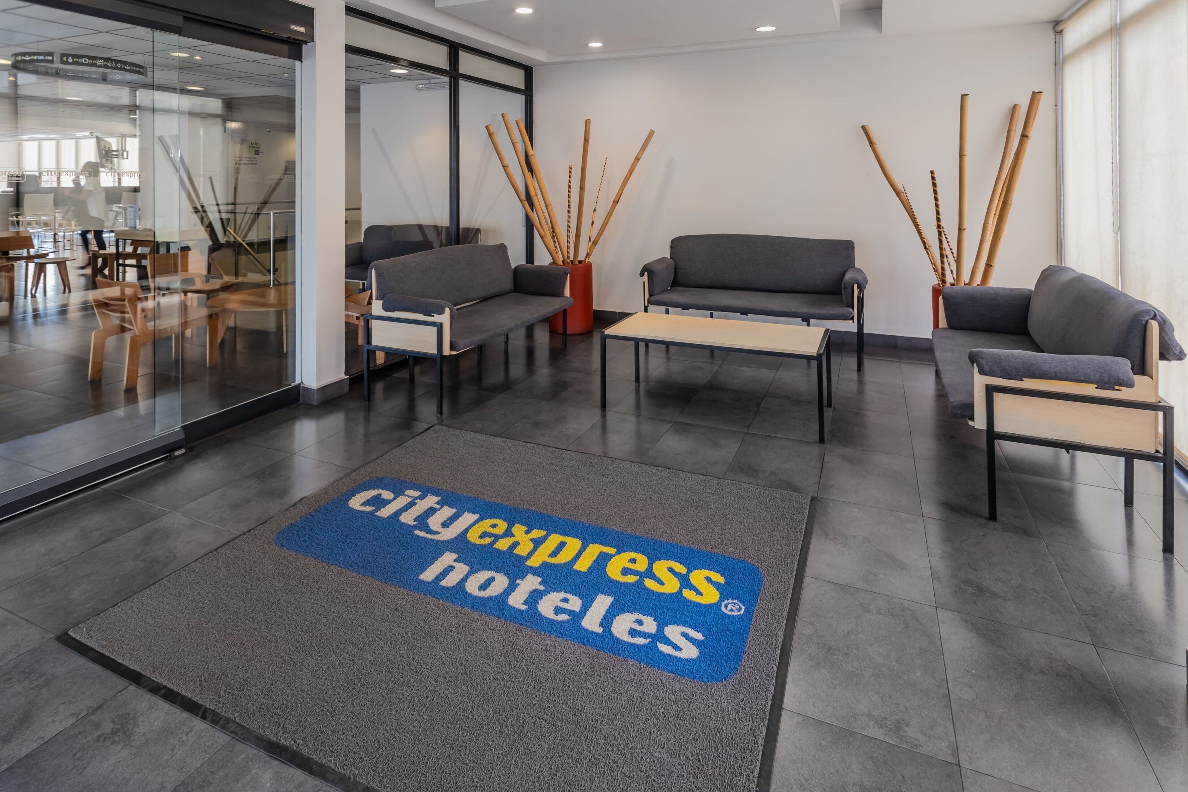 A CityExpress hotel reception area with seating, a reception desk, and a glass wall.