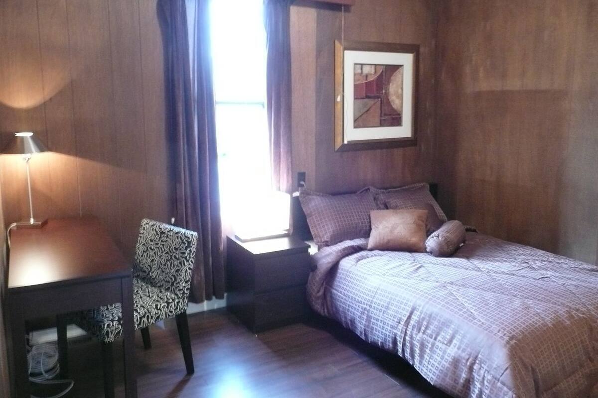 Een slaapkamer met een bed, bureau en stoel.