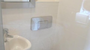 Een badkamer met een wastafel, toilet en spiegel.