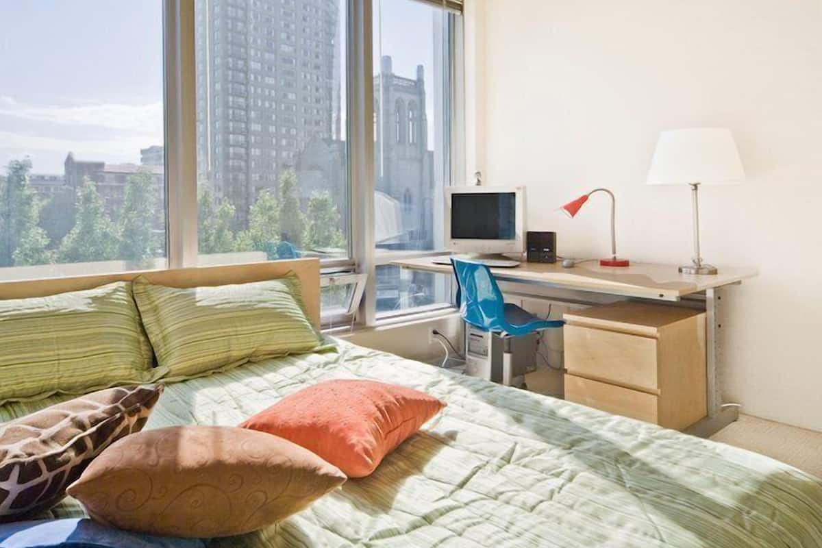 A bedroom with a bed, a desk, a chair, and a computer.