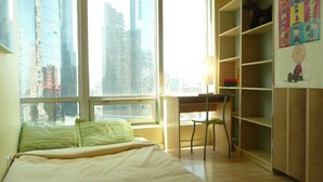 A bedroom with a bed, a desk, and a chair. There is a window with a city view. - MondeLiving City Condo (Vancouver)