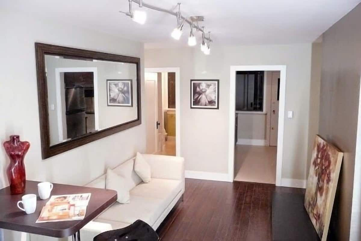 A modern living room with a sofa, a coffee table, a mirror, and framed pictures on the walls.