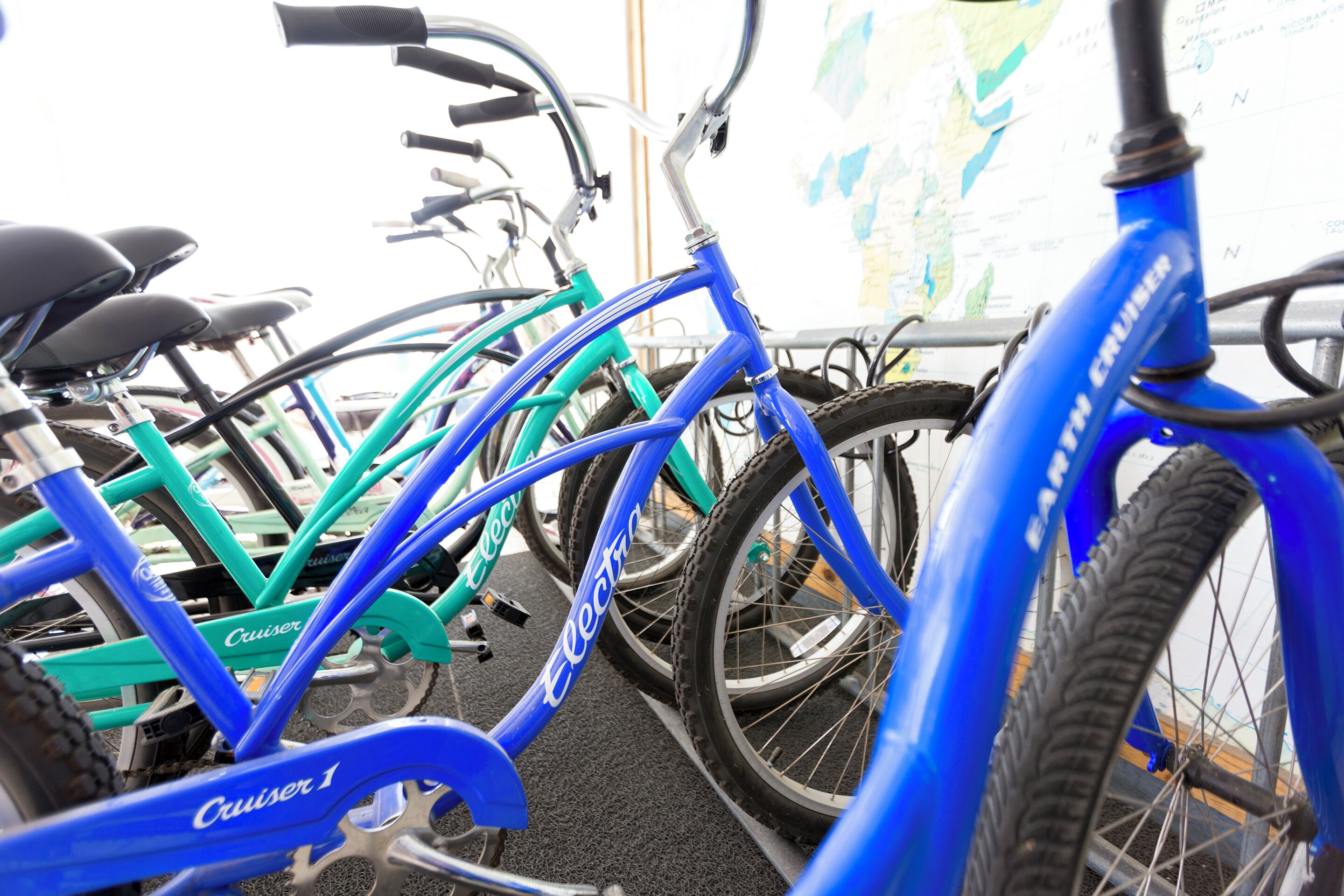 A row of bicycles, including a blue one with 'Cruiser' written on it, parked indoors.