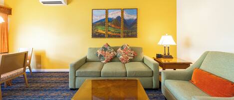 A living room with a sofa, a coffee table, a lamp, and a painting on the wall.