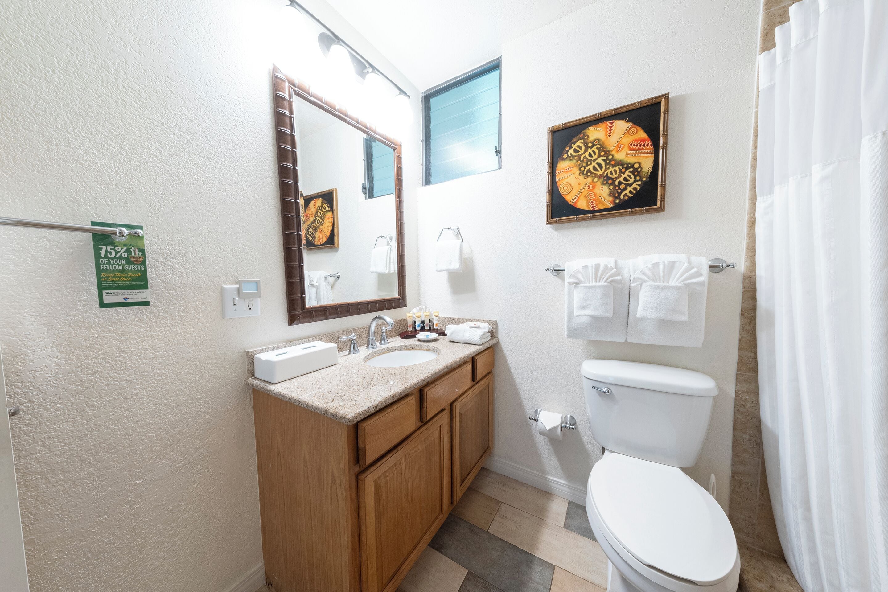 Une salle de bain équipée d’un lavabo, d’un miroir, de toilettes et d’un rideau de douche.