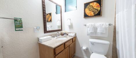 A bathroom with a sink, mirror, toilet, and shower curtain.