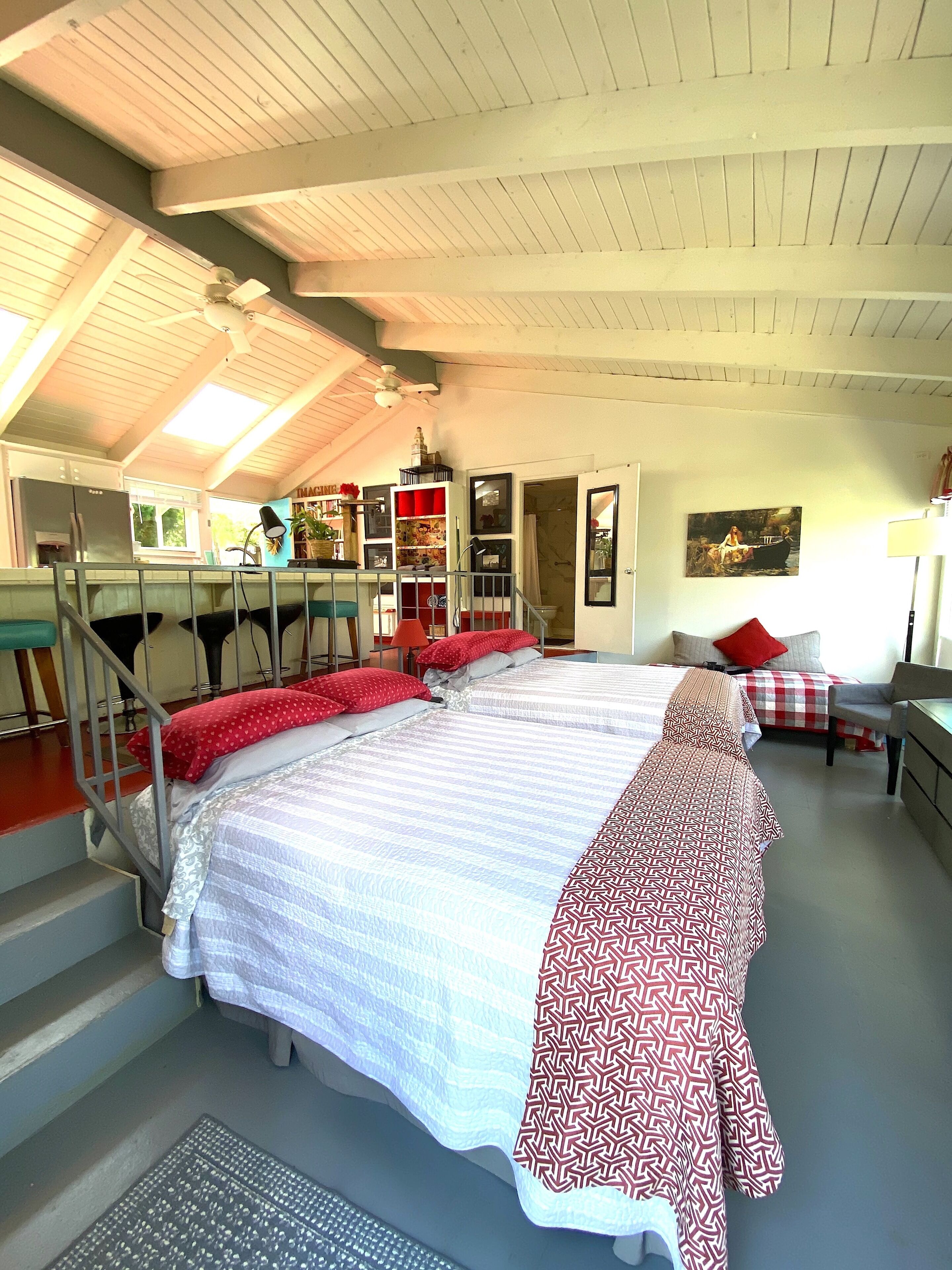 Ein Schlafzimmer mit zwei Betten, einer Treppe, einem Schreibtisch und einem Bücherregal.