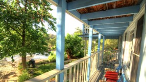 A covered porch with blue railings and red cushioned chairs.