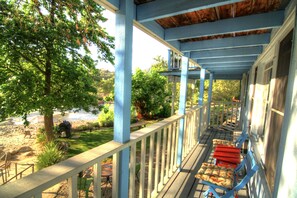 A covered porch with blue railings and red cushioned chairs.