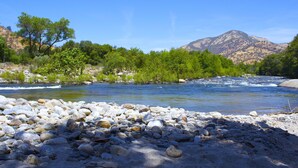 Une rivière aux rives rocheuses, avec des arbres en arrière-plan.