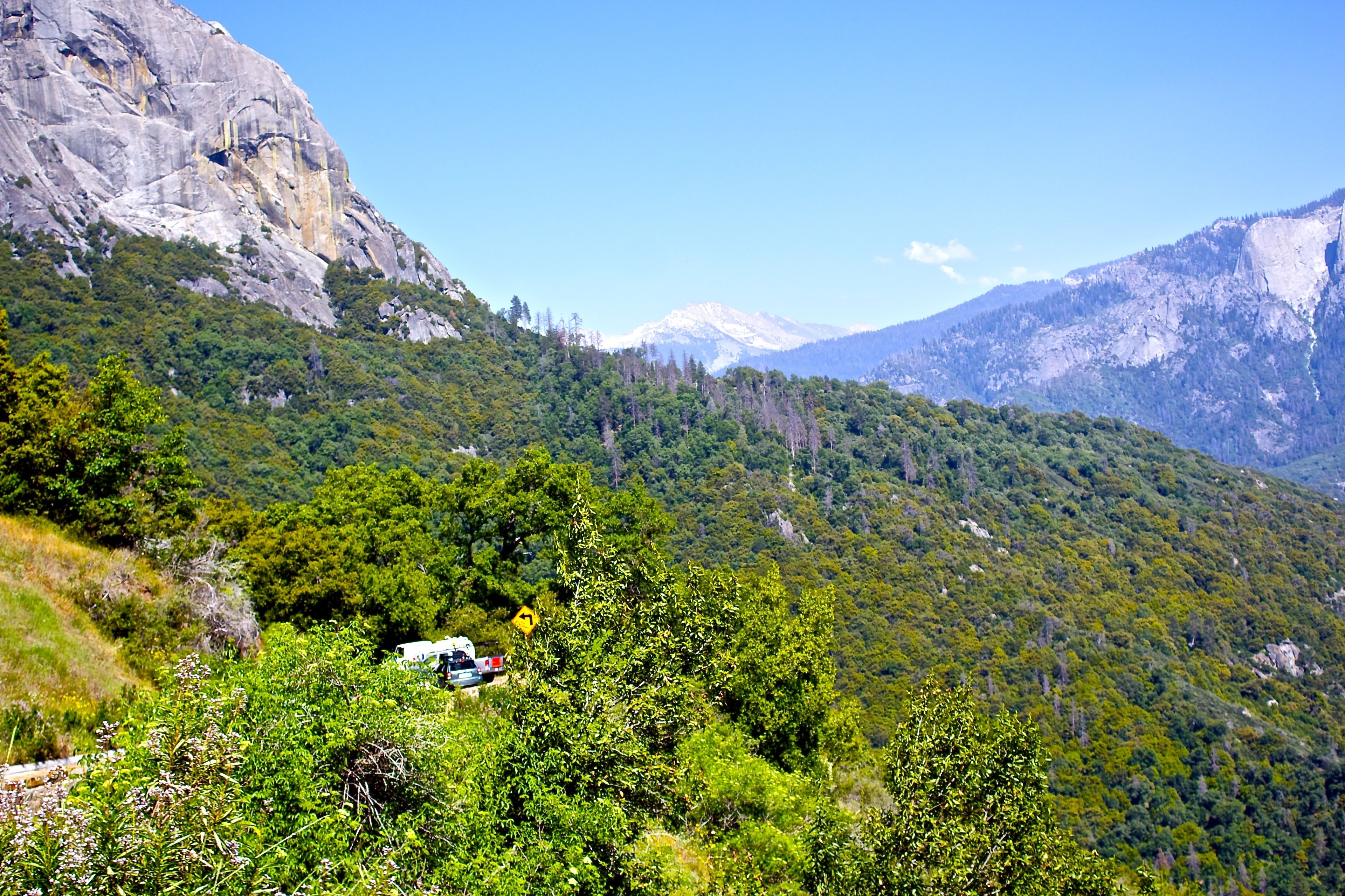 A mountainous landscape with a vehicle parked on a slope.