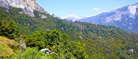 A mountainous landscape with a vehicle parked on a slope.