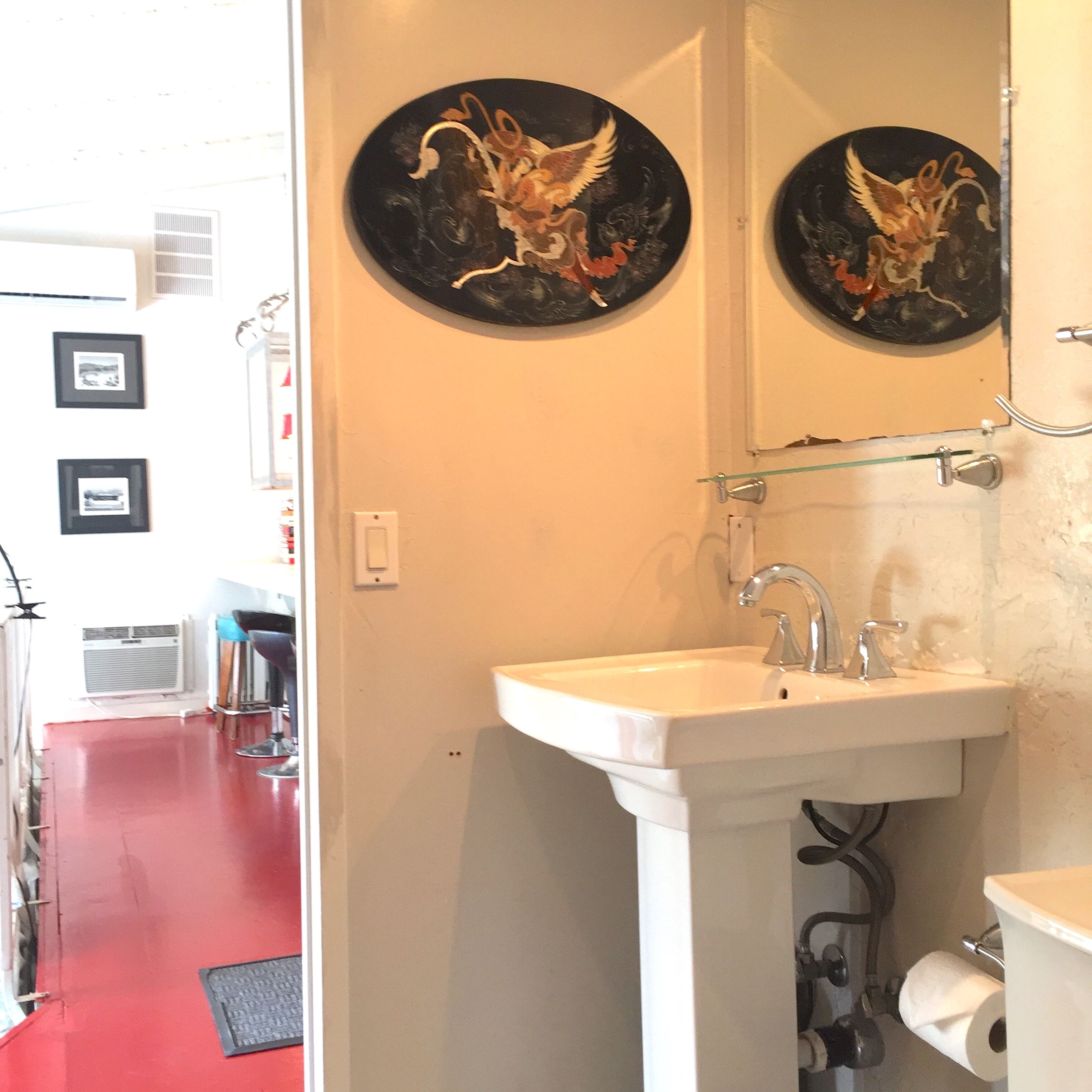 A bathroom with a white sink, a mirror, and two decorative plates with an angelic design.