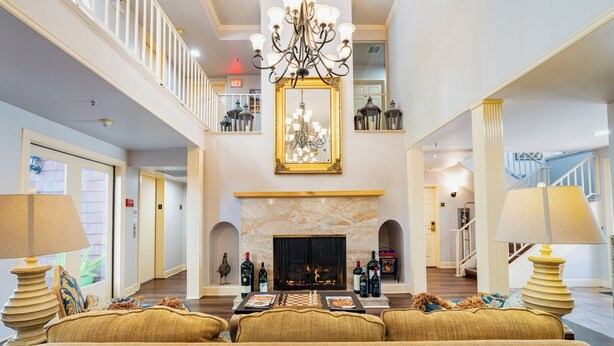 A spacious lobby with a fireplace, chandeliers, and a high ceiling. - Elm House Inn (Napa)