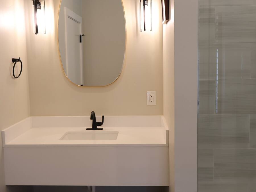 A modern bathroom with a white vanity, a large mirror, and two wall-mounted lights.