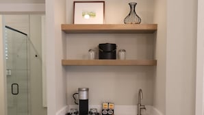 A compact kitchen with a built-in dishwasher, a sink, and a hanging light fixture above the countertop. - Elm House Inn (Napa)