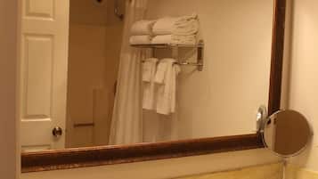 A bathroom with a sink, three wall-mounted lights, a mirror, and a towel rack with folded towels.