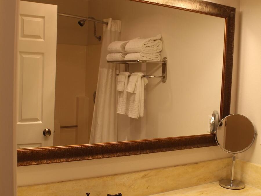 A bathroom with a sink, three wall-mounted lights, a mirror, and a towel rack with folded towels.