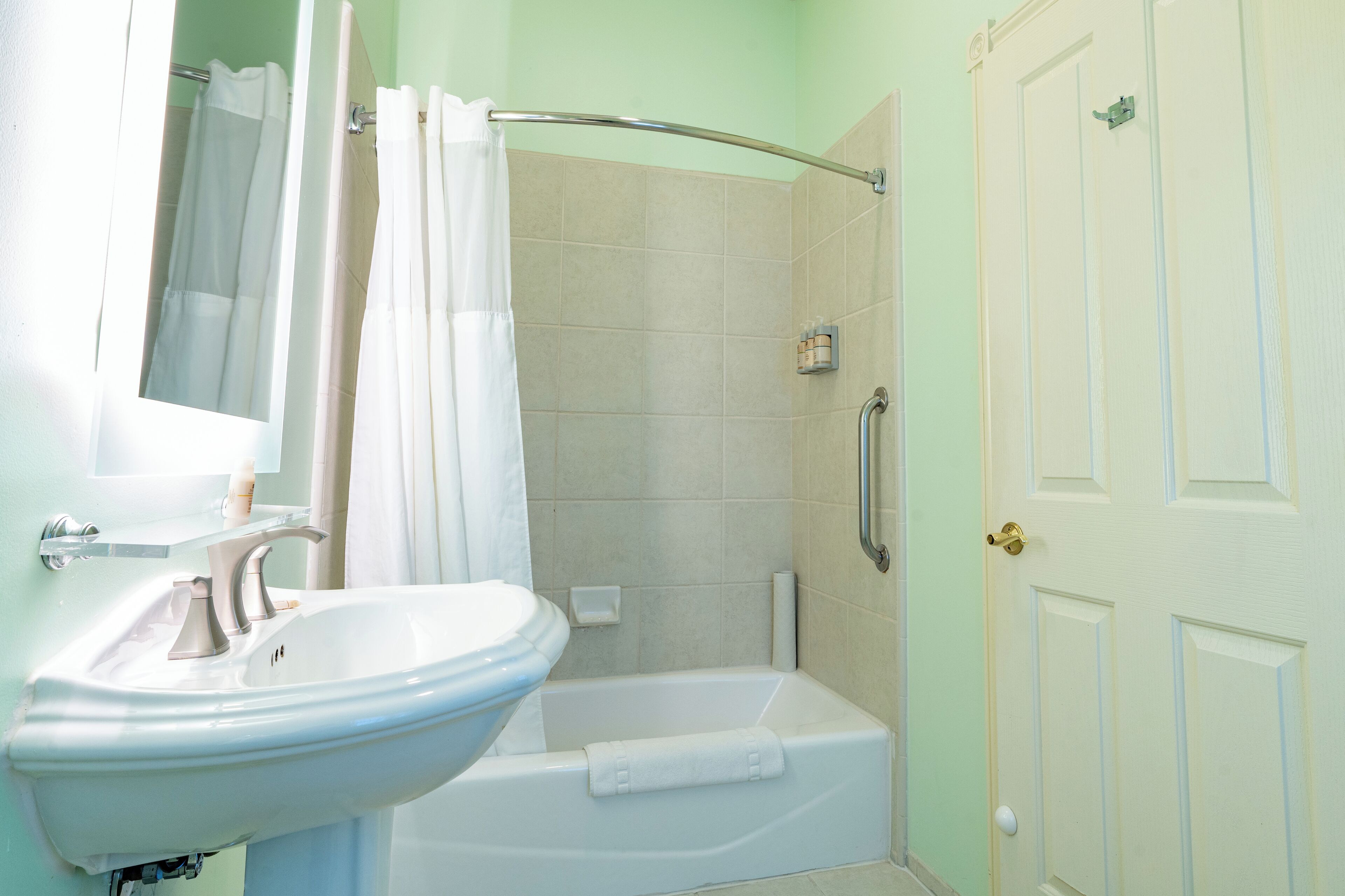 Un baño con lavamanos, espejo, ducha y bañera.
