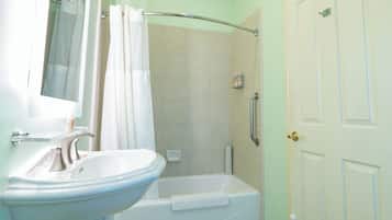Un baño con lavamanos, espejo, ducha y bañera.