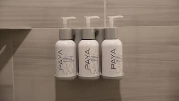 Trois flacons de shampoing et d’après-shampoing PAYA, placés dans un distributeur mural.
